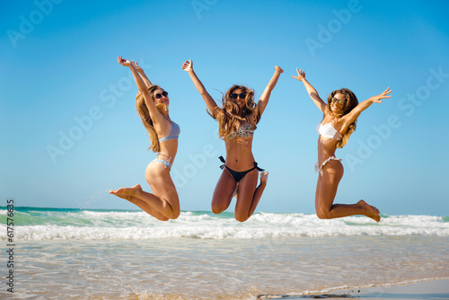 Beautiful teenage friends jumping on the beach
