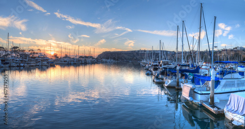 Sunset over sailboats in the calm water of the Dana Point harbor in Southern California, USA