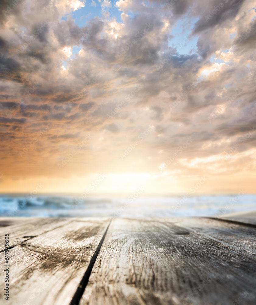Obraz premium Wooden table and sunset at seaside. Focus on table, blurred background.