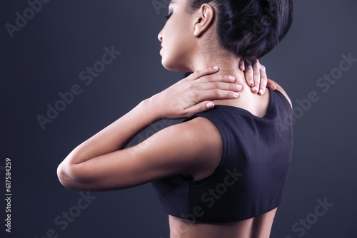 Body pain. Studio shot of beautiful young woman with dark brown hair. Woman suffering from neck ache