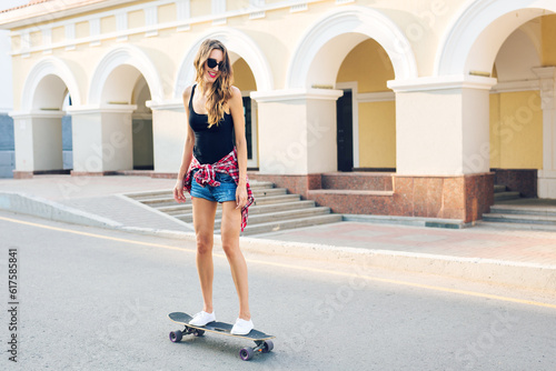 summer holidays, extreme sport and people concept - happy girl riding skateboard on city street.