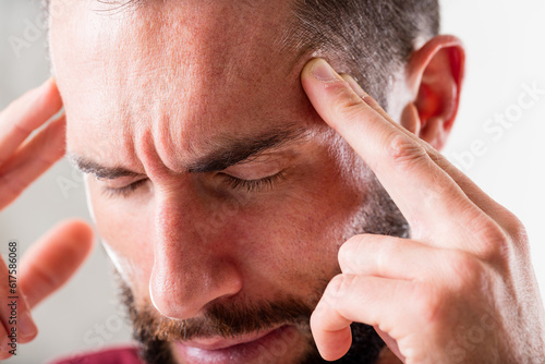 Fotografie man that seems to suffer a severe headache holding his head with hands or pointi