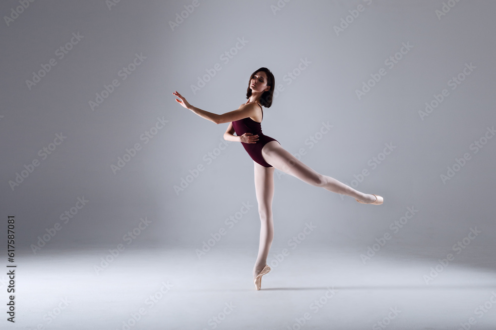 Slim ballerina is dancing in the white studio in the contrast light