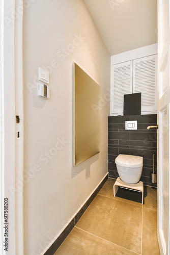a modern bathroom with black and white tiles on the walls, toilet in the fore - doord corner next to the sink photo