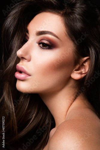 Glamour portrait of beautiful girl model with makeup and romantic wavy hairstyle. Fashion shiny highlighter on skin, sexy gloss lips make-up and dark eyebrows.