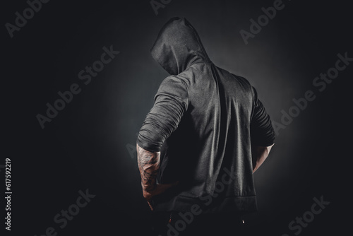 Back view of muscular male bodybuilder posing in studio over black background