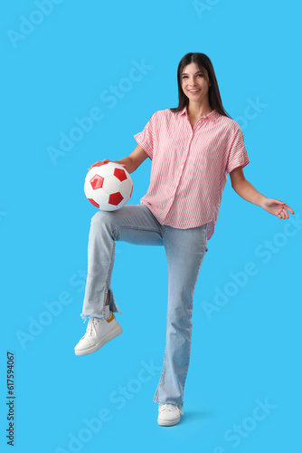 Young woman playing with soccer ball on blue background © Pixel-Shot