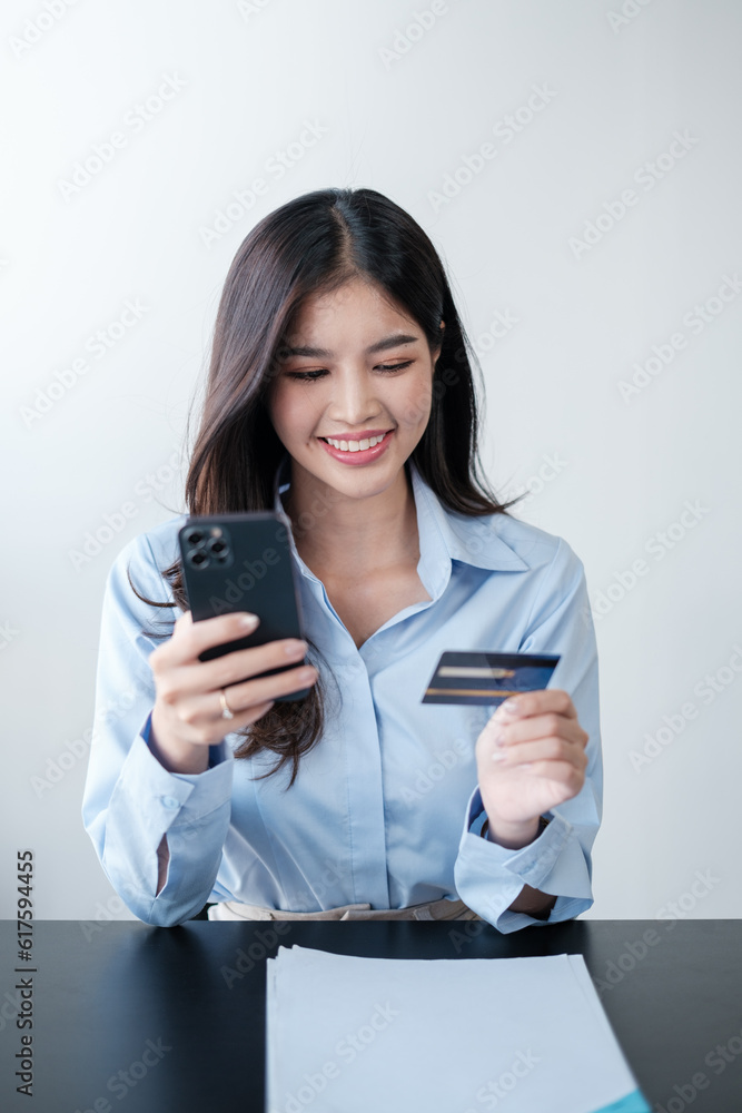 Beautiful Asian woman with smart phone and credit card, she fills in credit card information to pay for goods and services, online shopping concept pay by credit card via smartphone. Beautiful Asian woman with smart phone and credit card, she fills in credit card information to pay for goods and services, online shopping concept pay by credit card via smartphone.