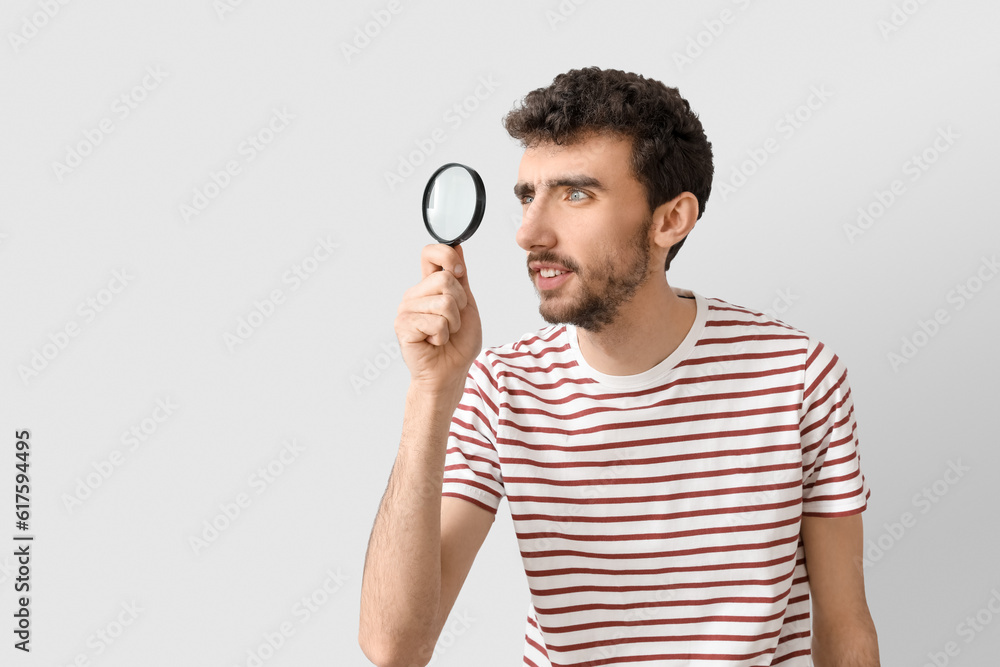 Young man with magnifier on light background Young man with magnifier on light background