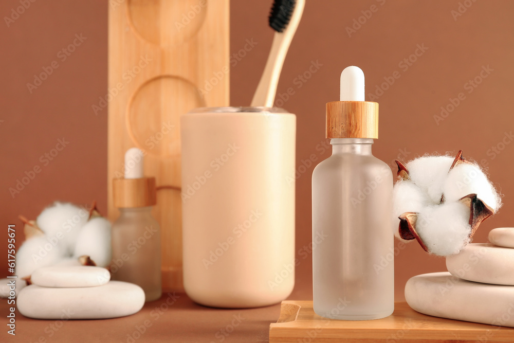 Bottles of essential oil, toothbrush, spa stones and cotton flowers on color background, closeup