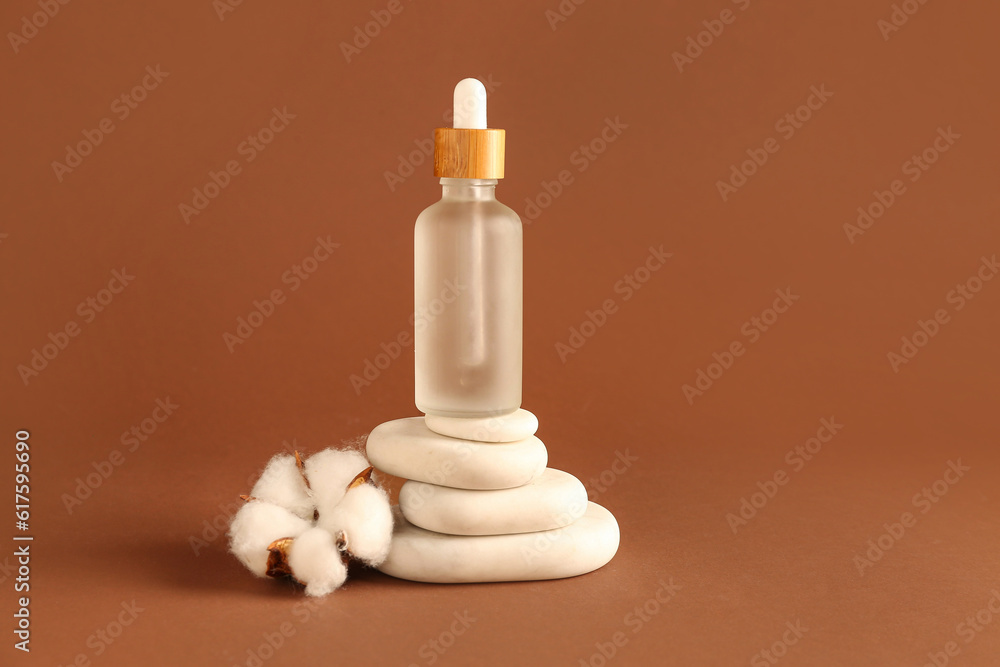 Bottle of essential oil, spa stones and cotton flower on color background Bottle of essential oil, spa stones and cotton flower on color background