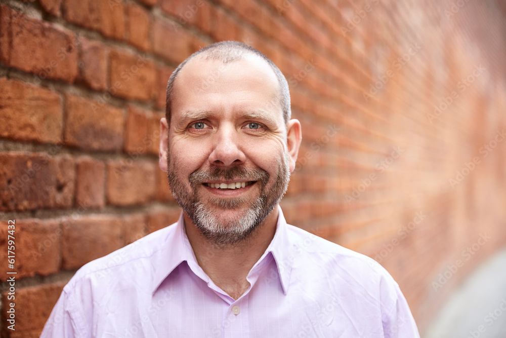 Fototapeta premium Portrait of smiling man against a brick wall background.