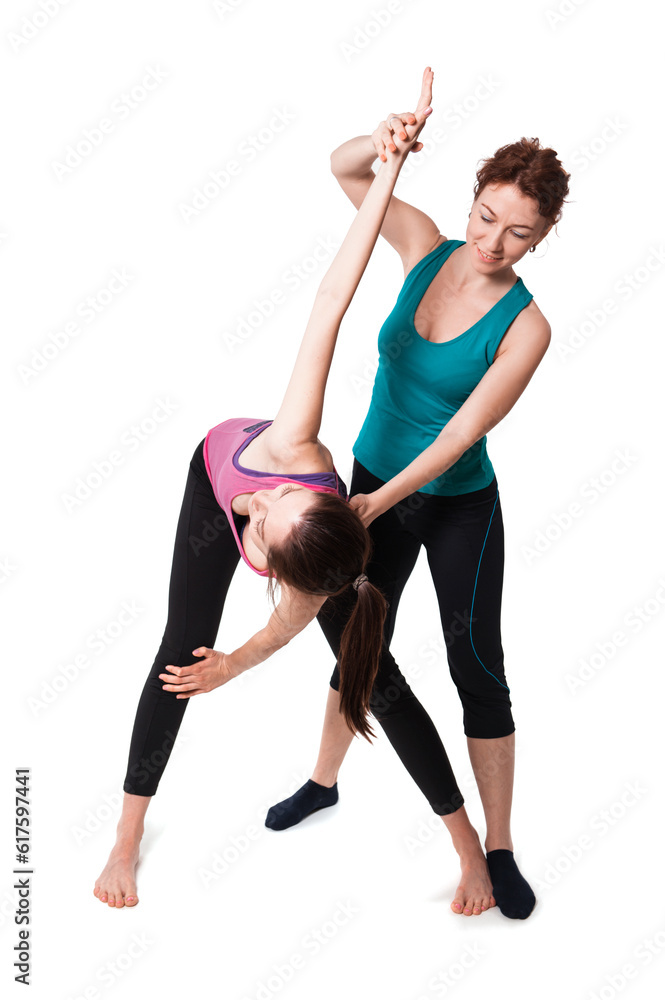 Young woman helping another young woman with positioning on her yoga pose. Young woman helping another young woman with positioning on her yoga pose.
