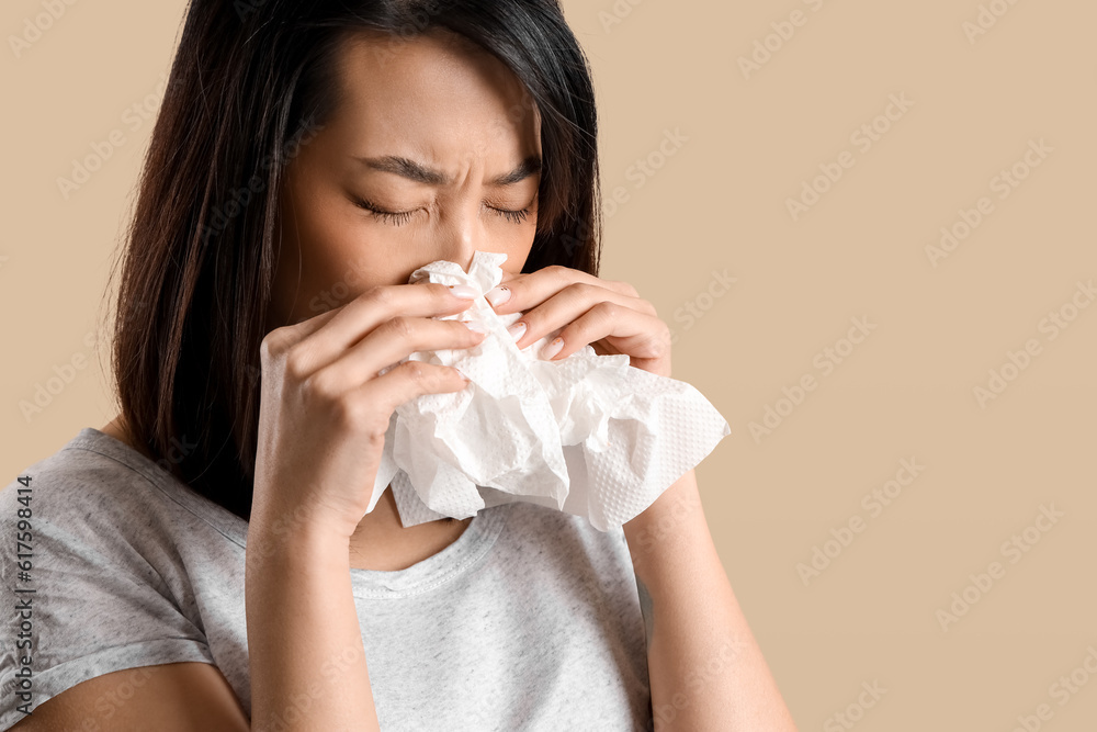 Ill Asian woman with tissues on beige background, closeup Ill Asian woman with tissues on beige background, closeup