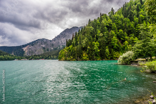 The emerald green lake framed by the forest and mountains in the gloomy rainy weather © Designpics