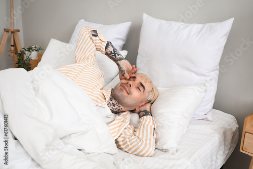 Young tattooed man waking up in bedroom