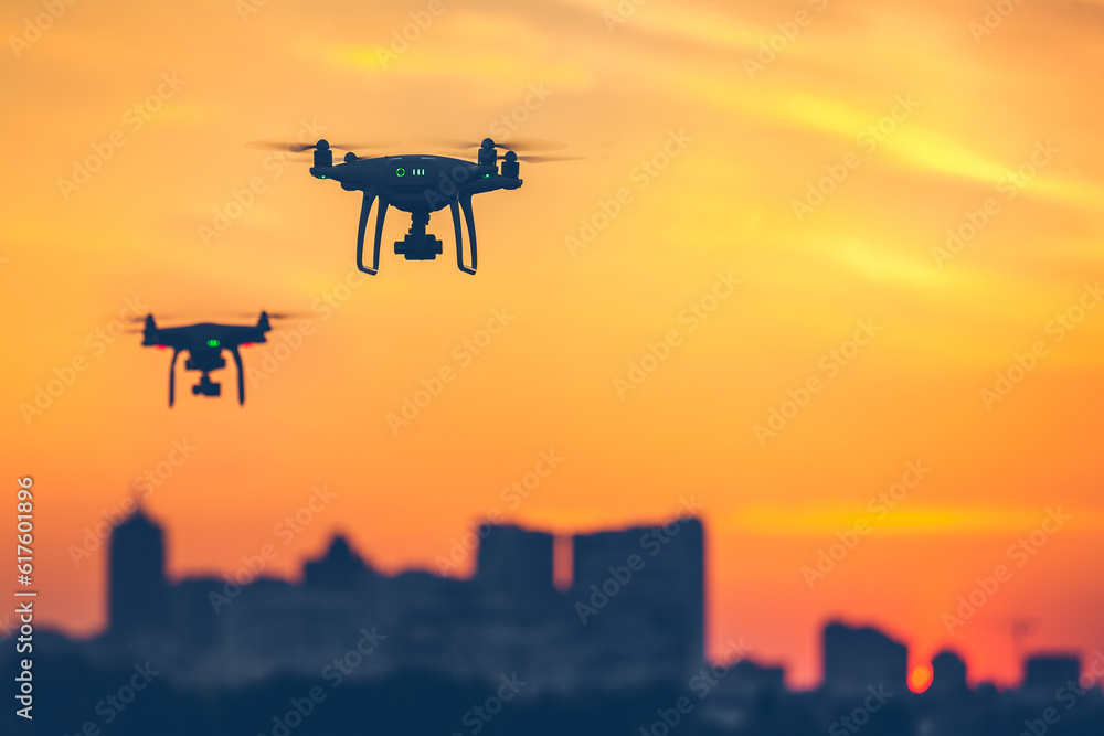 Two modern Remote Control Air Drones Fly with action cameras in dramatic sunset sky. Cityscape silhouette in the background. Modern technologies. Kiev, Ukraine. Travel, hobby, inspiration. Copy space