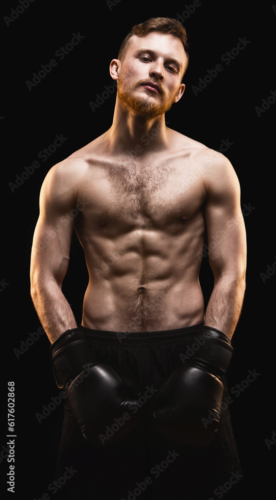 Fototapeta premium Bearded athlete with boxing gloves on black background