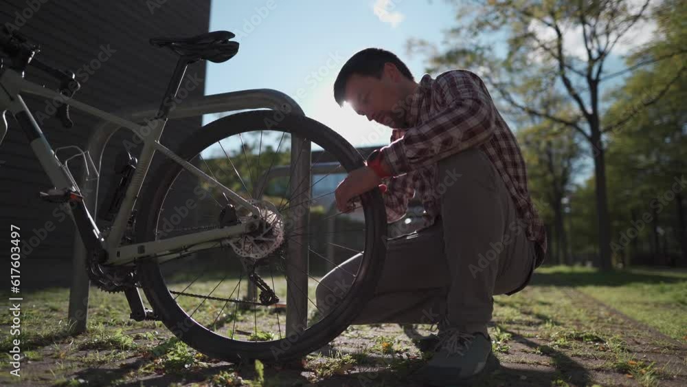 Man inflates tire with small hand pump in a bicycle parking lot in Germany. The topic is amateur bicycle maintenance, repair and adjustment. A cyclist pumping up a tire on a Gerevel bike in the city. Man inflates tire with small hand pump in a bicycle parking lot in Germany. The topic is amateur bicycle maintenance, repair and adjustment. A cyclist pumping up a tire on a Gerevel bike in the city.