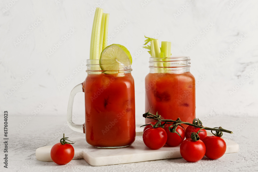 Mason jars of bloody mary with celery and tomatoes on white table Mason jars of bloody mary with celery and tomatoes on white table
