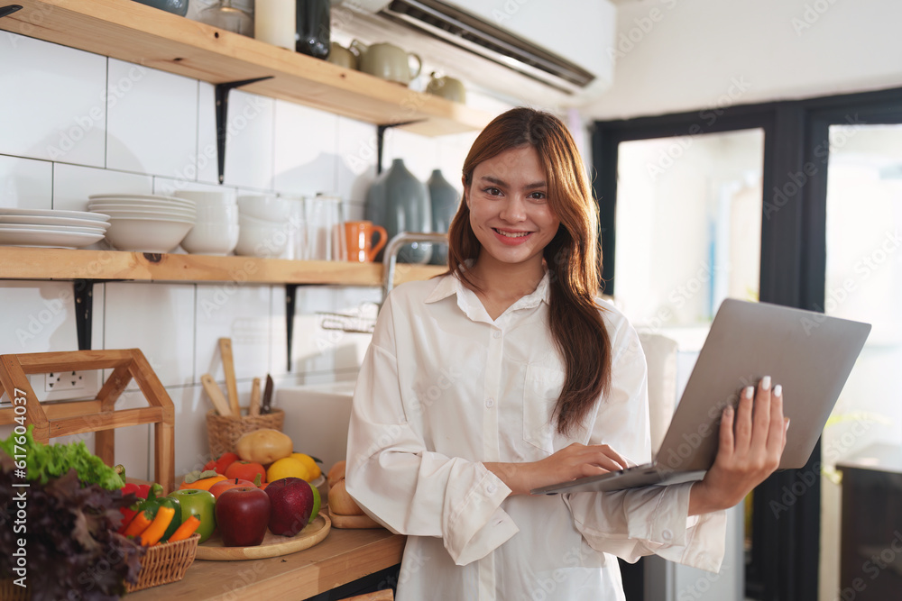 Portrait of a young cheerful asian woman at kitchen room with healthy raw food. Vegetarianism, wellbeing and healthy lifestyle concept Portrait of a young cheerful asian woman at kitchen room with healthy raw food. Vegetarianism, wellbeing and healthy lifestyle concept