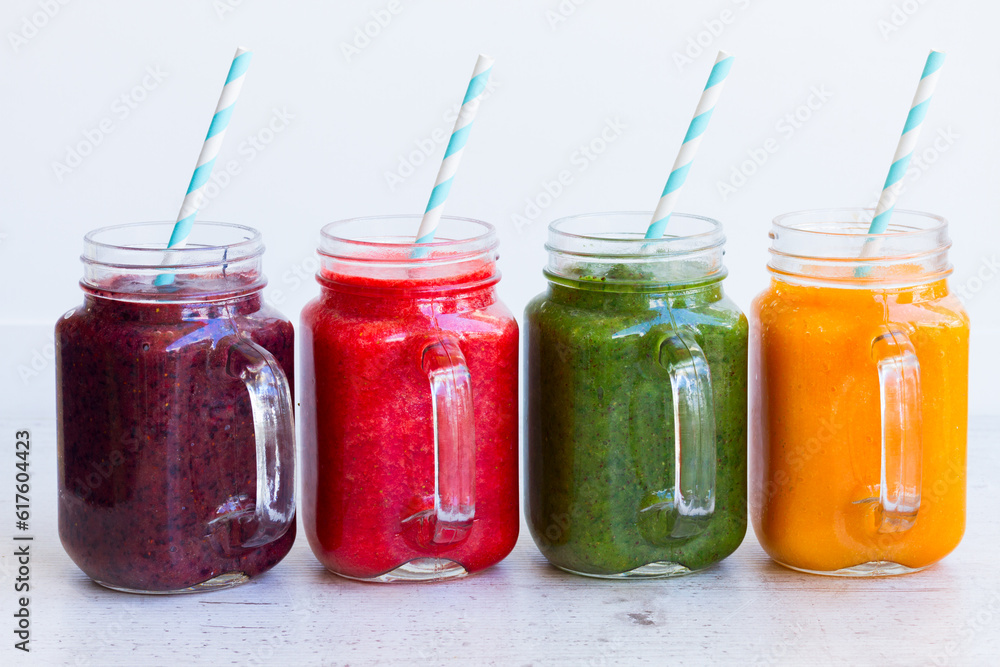 Colorful smoothie drinks in glass jars on white table close up Colorful smoothie drinks in glass jars on white table close up