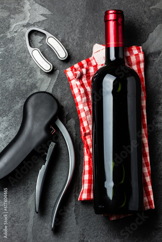 Bottle of red wine with corksrew and italian napkin on slate background. Top view photo
