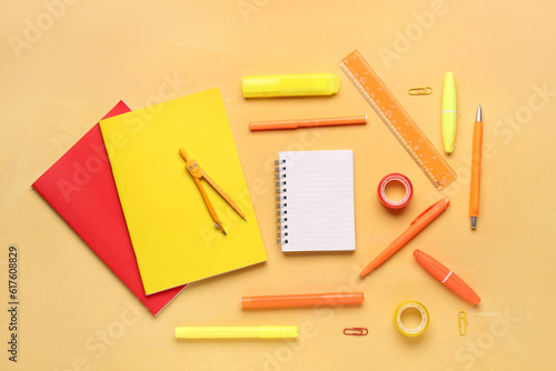 Notebooks with different school stationery on orange background
