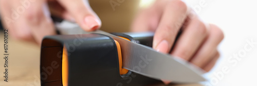 Tableau sur toile Woman sharpening knife with special knife sharpener