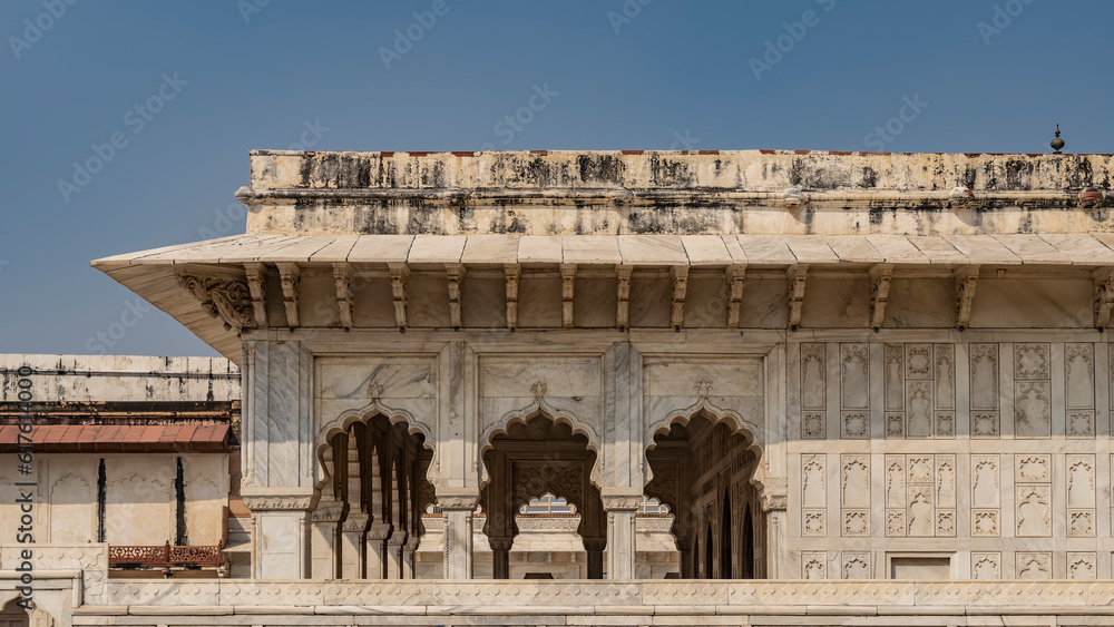 The pavilion in the ancient Indian palace of Diwan-i-Khas in the Red Fort. Colonnade with elegant arches, carved marble walls. Blue sky. Agra. India.