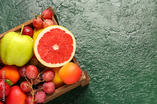 Fototapeta Naklejka Na Ścianę i Meble -  Wooden box with different fresh fruits on green table