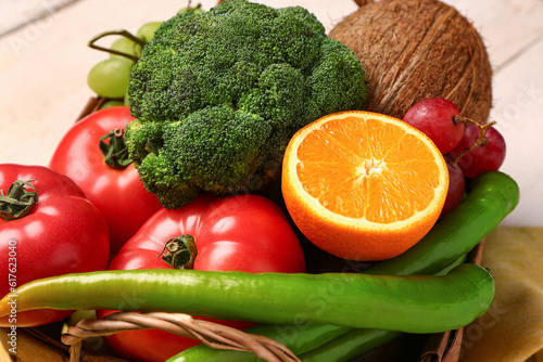 Wicker basket with different fresh fruits and vegetables on table  closeup