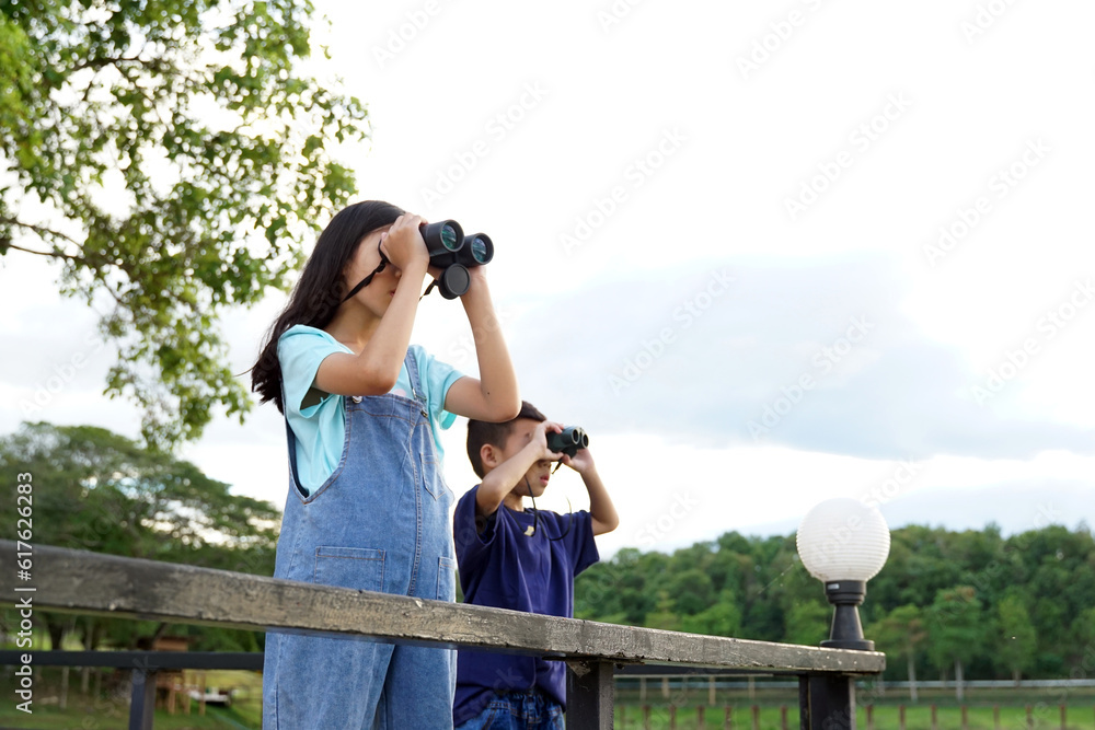 Children use binoculars to look at nature, birds, animals in the national park during family camping on vacation. with the concept of learning outside the classroom nature study, exploration. 
