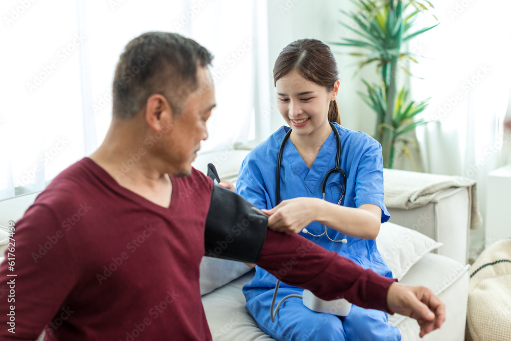 Fototapeta premium Caregiver nurse measuring blood pressure by using digital sphygmomanometer Senior patient at home. Caregiver nurse using medical device to measure blood pressure Senior patient.