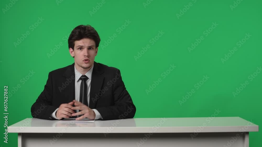TV Live News Program: Presenter Reporting. Anchorman corrects the sheets of paper, Talks, Listens, Nods against the background of a green screen. Advertising area, workspace mock up. TV Live News Program: Presenter Reporting. Anchorman corrects the sheets of paper, Talks, Listens, Nods against the background of a green screen. Advertising area, workspace mock up.