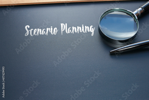The word Scenario Planning is written on the black chalkboard with a pen, and magnifying glass