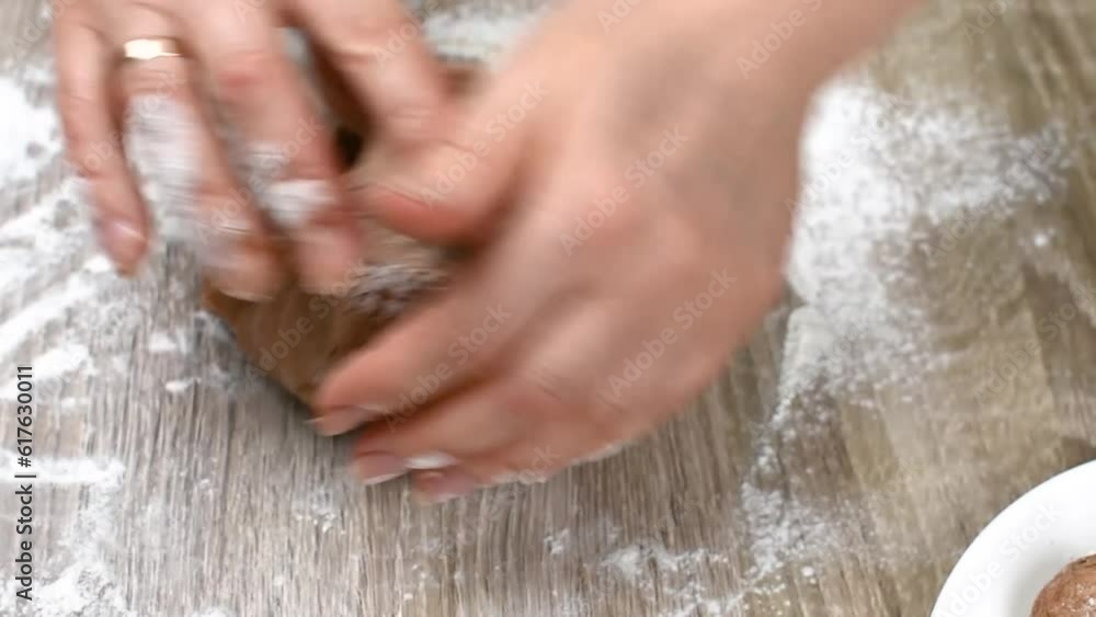 Close-up view of female hands kneading the dough in flour on the table. The baker prepares the dough Close-up view of female hands kneading the dough in flour on the table. The baker prepares the dough