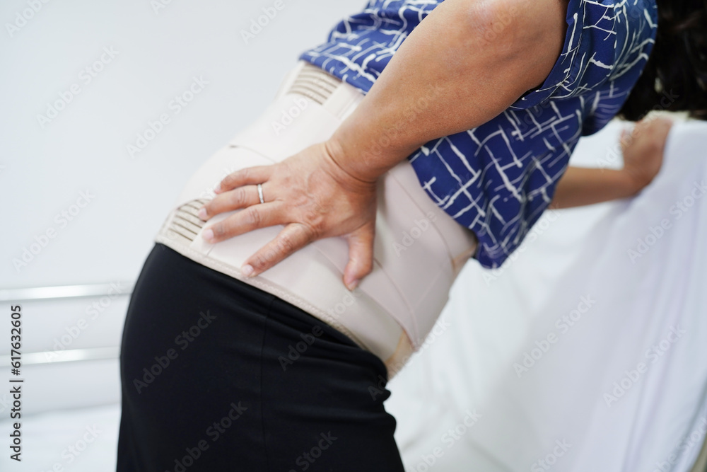 Fototapeta premium Asian senior pain back wearing elastic support belt with walker.