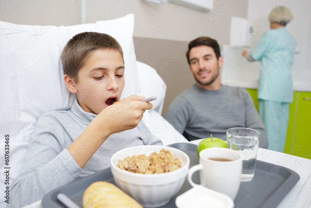 boy with breakfast in bed in hospital with his father boy with breakfast in bed in hospital with his father