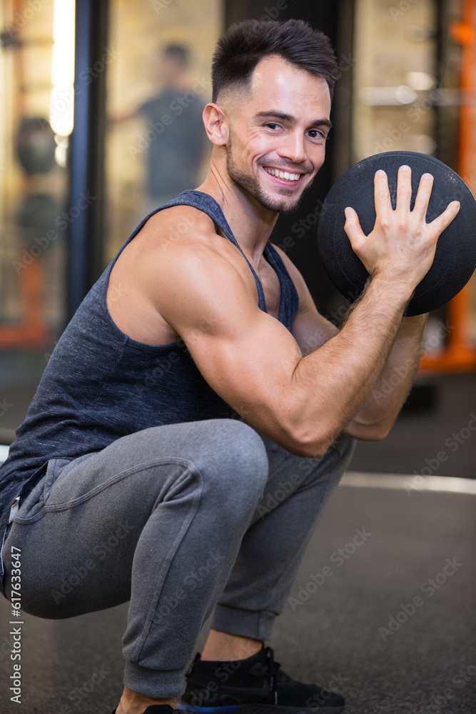 man holding a ball doing squats in the gym man holding a ball doing squats in the gym