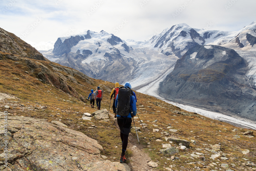 Panorama view with mountain Dufourspitze (left), Gorner Glacier, mountain Lyskamm (right) and group of mountaineers hiking towards mountain massif Monte Rosa in Pennine Alps, Switzerland