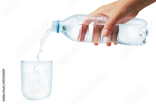 Pouring water from a plastic bottle into a glass cup.