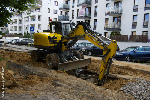 An excavator standing on a road under construction  housing estate in the background  Road repair  road closed  infrastructure renovation