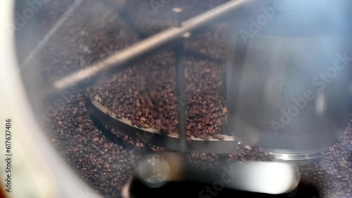 Production of fresh fried coffee beans roasting factory process. Prepared coffee beans mixed around on a cooling plate of an oven photo