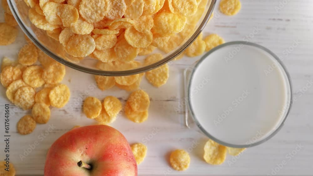Serving breakfast with corn flakes in bowl glass of milk and fresh apple on wooden table top view Serving breakfast with corn flakes in bowl glass of milk and fresh apple on wooden table top view