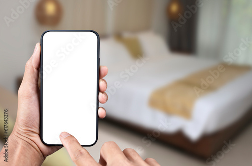 Hand holding black smartphone with transparent screen  and  bedroom background, Mobile phone frameless design application booking hotel concept and PNG file