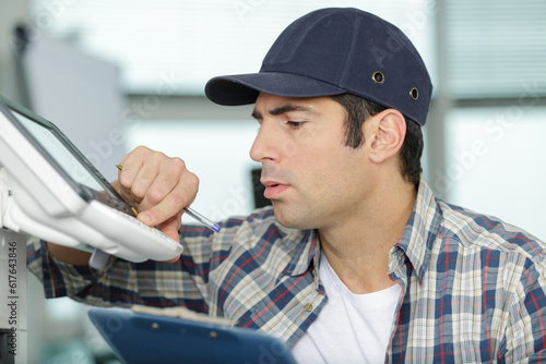 male technician is repairing a printer in an office