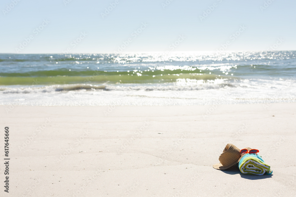 Red sunglasses, sunhat and rolled beach towel on sunny sand beach by the sea, copy space Red sunglasses, sunhat and rolled beach towel on sunny sand beach by the sea, copy space