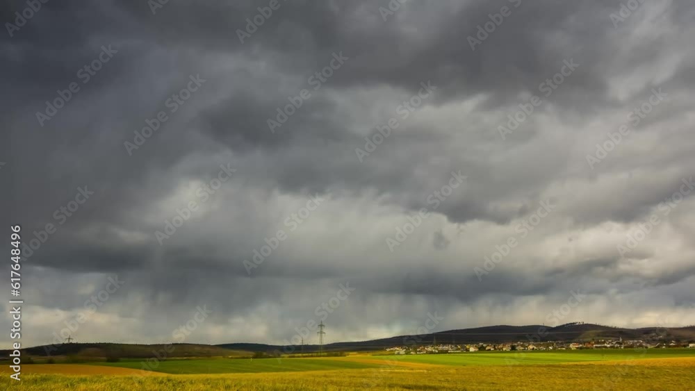 timelapse with a colorful field and a mountain with a forest during dense dark rainclouds and storm timelapse with a colorful field and a mountain with a forest during dense dark rainclouds and storm