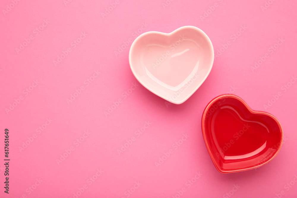Red and pink heart shaped bowls on pink background.